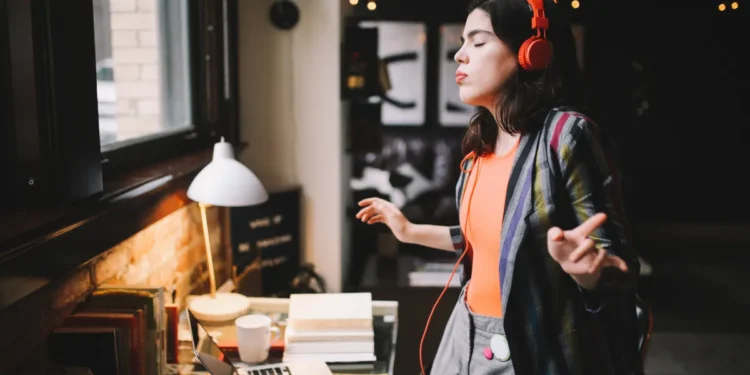 Gandeng Deezer - Winamp lahir kembali lewat pemutar musik baru 1 Young Latinx woman sitting at the desk in her Los Angeles apartment, receiving happy news over the social networks or just having a nice day, dancing to the music.